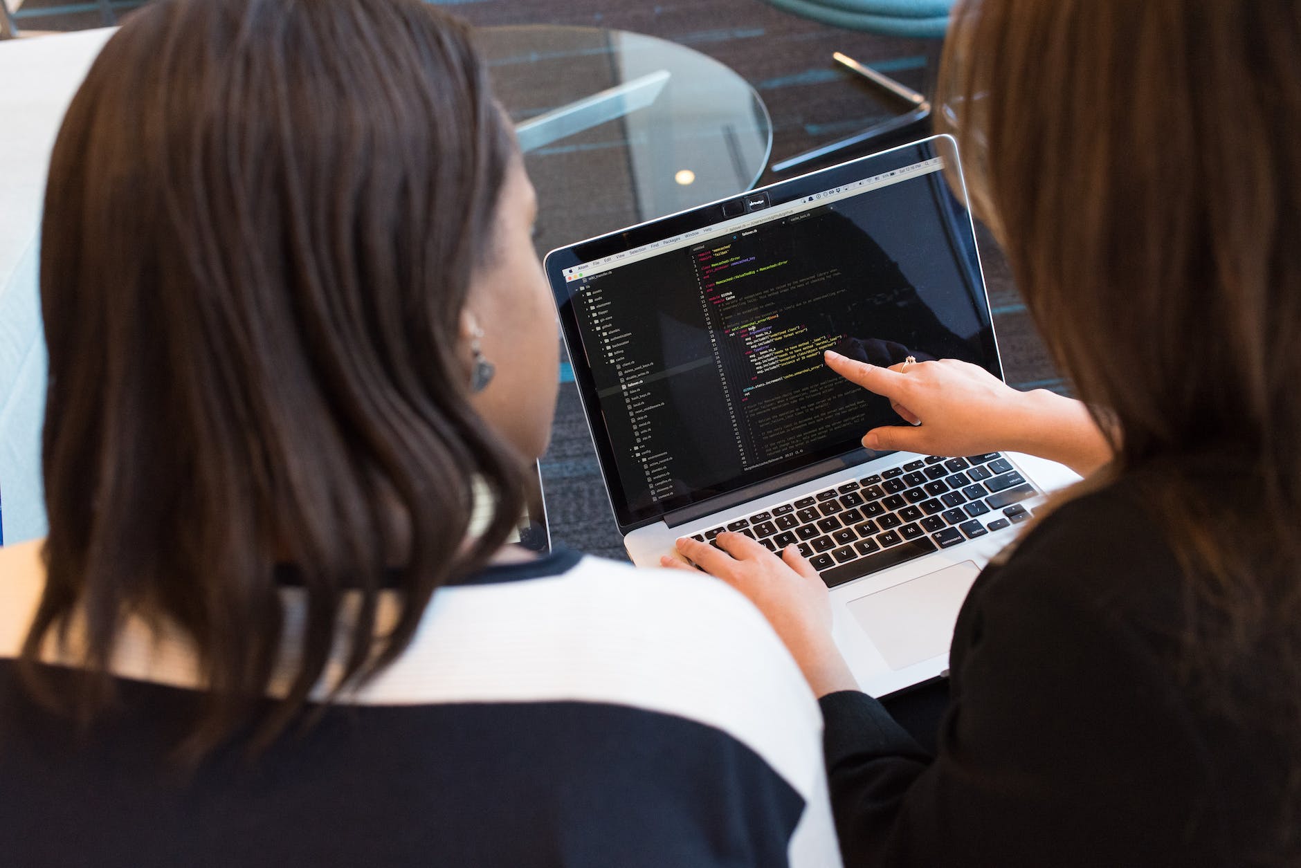 two women looking at the code at laptop